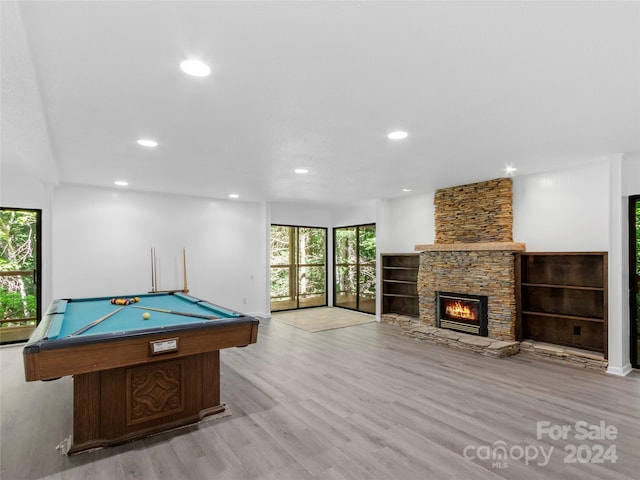 game room with billiards, a stone fireplace, and light hardwood / wood-style floors