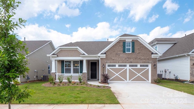 craftsman-style house with a front yard, cooling unit, covered porch, concrete driveway, and brick siding