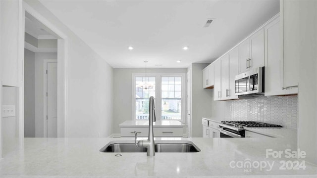 kitchen with a sink, light stone counters, stainless steel appliances, white cabinets, and decorative backsplash