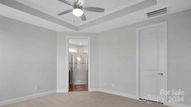 carpeted empty room featuring a raised ceiling and ceiling fan