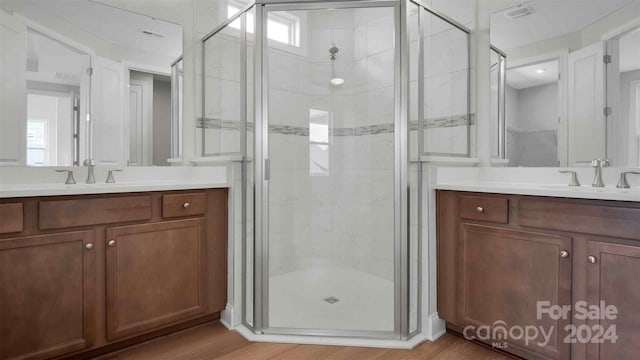 bathroom featuring hardwood / wood-style floors, vanity, and a shower with shower door