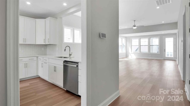 kitchen featuring white cabinets, backsplash, stainless steel dishwasher, and sink