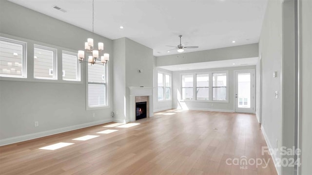 unfurnished living room featuring a premium fireplace, ceiling fan with notable chandelier, and light wood-type flooring