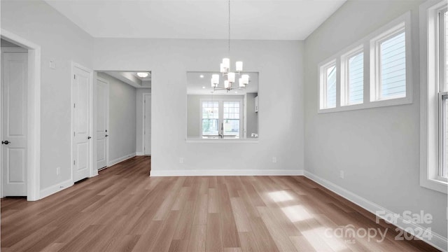 unfurnished dining area featuring a chandelier and light hardwood / wood-style floors