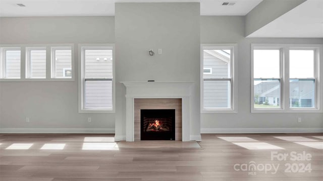 unfurnished living room featuring a wealth of natural light, light wood-type flooring, and a high end fireplace