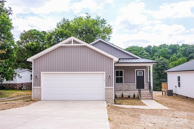 view of front of home with central air condition unit, covered porch, and a garage