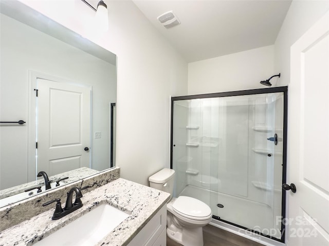 bathroom with hardwood / wood-style flooring, toilet, a shower with door, and vanity