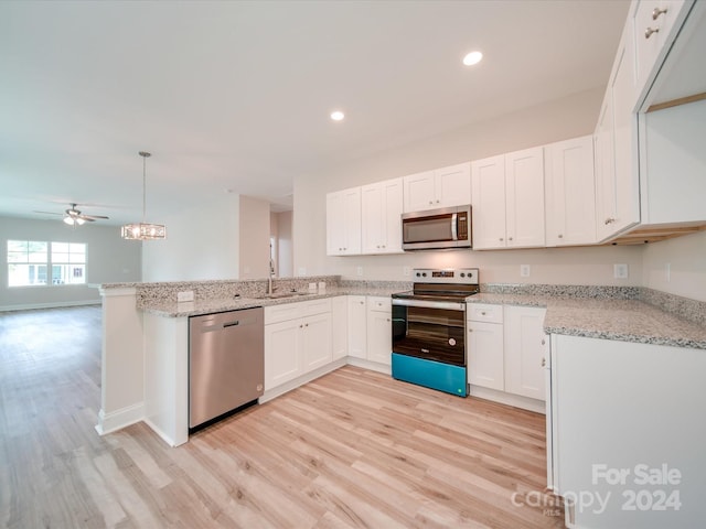 kitchen featuring decorative light fixtures, light hardwood / wood-style floors, kitchen peninsula, appliances with stainless steel finishes, and white cabinets