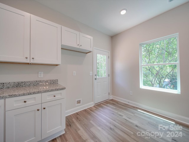 kitchen featuring light stone counters, white cabinets, and light hardwood / wood-style flooring