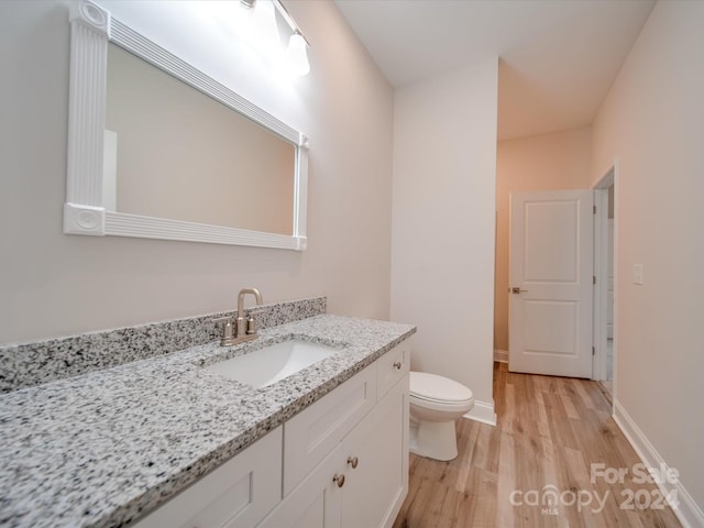 bathroom with hardwood / wood-style flooring, toilet, and vanity