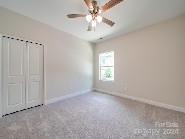 unfurnished bedroom featuring ceiling fan, a closet, and light colored carpet