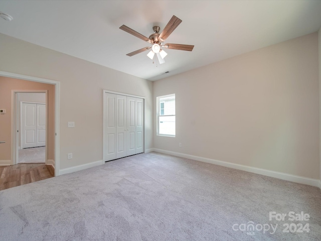 unfurnished bedroom with ceiling fan, light colored carpet, and a closet