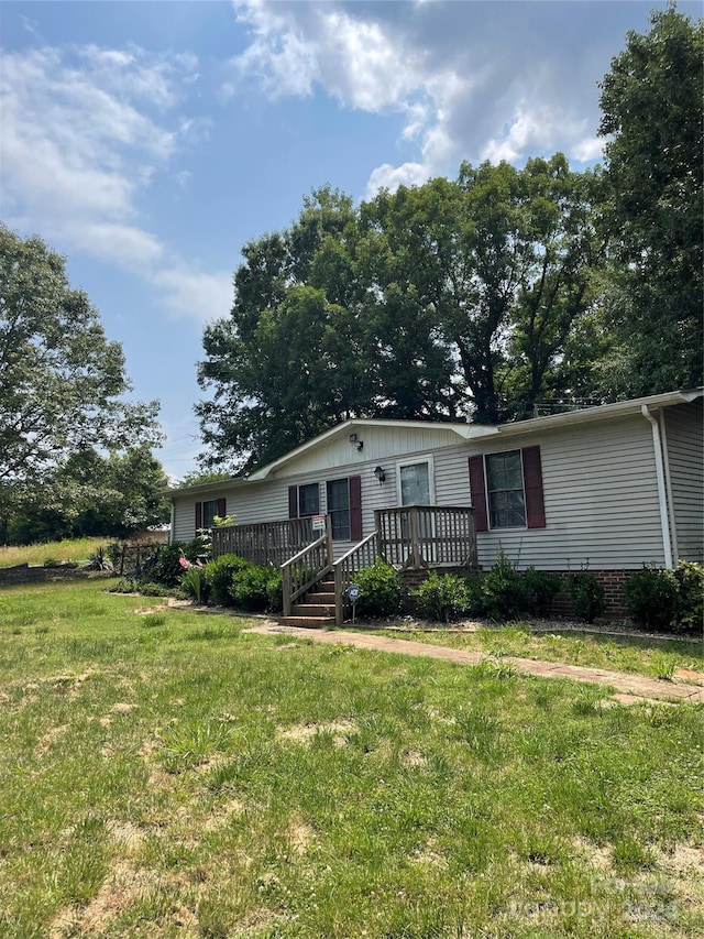 manufactured / mobile home featuring a wooden deck and a front yard