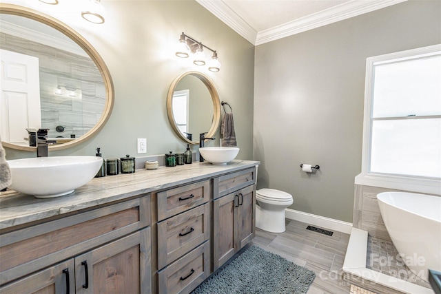 bathroom featuring toilet, ornamental molding, a bathtub, and vanity