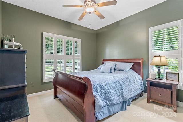 bedroom featuring ceiling fan, light carpet, and multiple windows