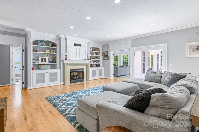 living room featuring french doors, crown molding, a textured ceiling, light hardwood / wood-style flooring, and built in features