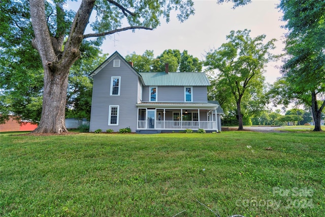 back of property featuring a yard and covered porch