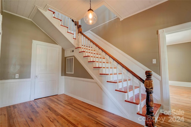 stairs featuring wood-type flooring and crown molding