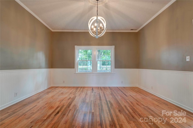 empty room with crown molding, a chandelier, and light hardwood / wood-style floors