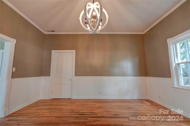 spare room with light wood-type flooring, a notable chandelier, and crown molding