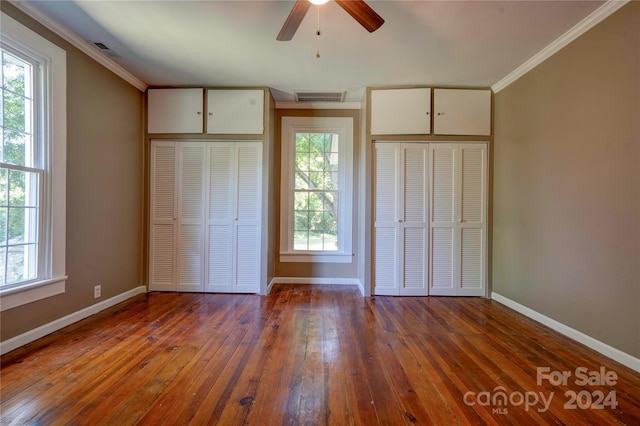 unfurnished bedroom with ceiling fan, light hardwood / wood-style flooring, ornamental molding, and multiple closets