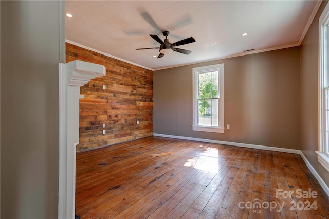 unfurnished room with ceiling fan, ornamental molding, hardwood / wood-style flooring, and wooden walls