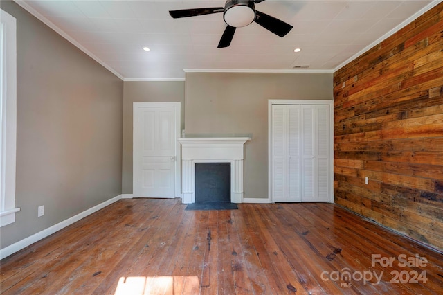 unfurnished living room featuring ceiling fan, wood walls, crown molding, and hardwood / wood-style flooring