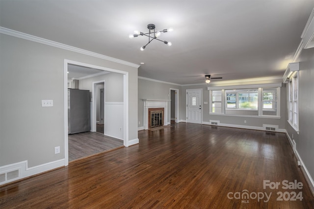 unfurnished living room featuring a fireplace, ceiling fan with notable chandelier, dark hardwood / wood-style floors, and crown molding