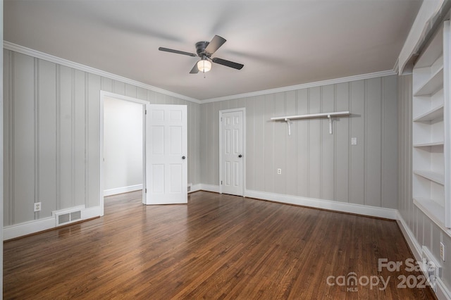 empty room with built in shelves, ceiling fan, dark hardwood / wood-style flooring, and ornamental molding