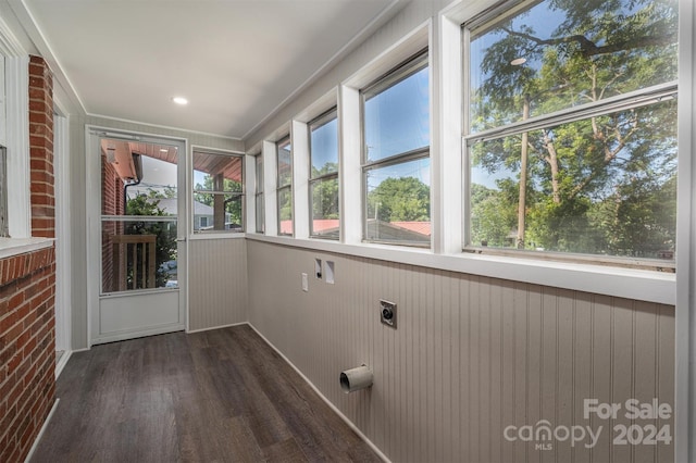 clothes washing area with hookup for an electric dryer, dark wood-type flooring, and brick wall