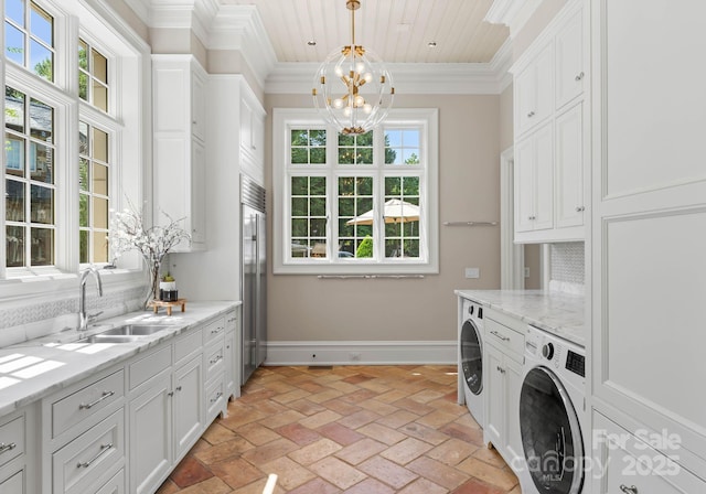 washroom with washer / dryer, an inviting chandelier, crown molding, and sink