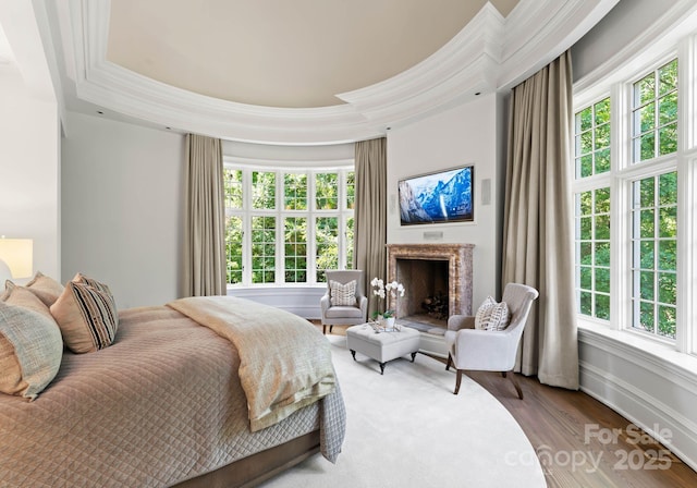 bedroom featuring wood-type flooring, a tray ceiling, multiple windows, and crown molding