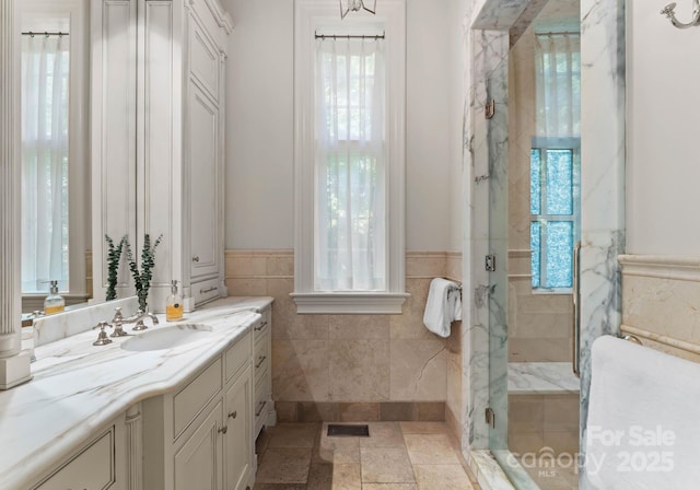 bathroom with a shower with door, vanity, and a healthy amount of sunlight