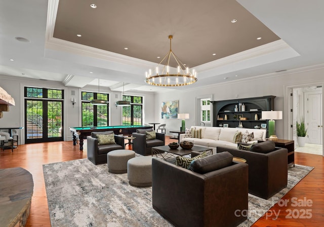 living room featuring a raised ceiling, light wood-type flooring, pool table, and french doors