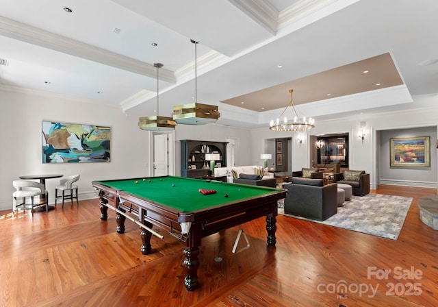 playroom featuring hardwood / wood-style flooring, a raised ceiling, ornamental molding, and an inviting chandelier