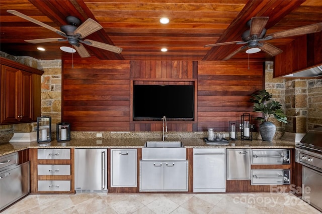 kitchen with wood walls, light stone counters, wooden ceiling, and sink