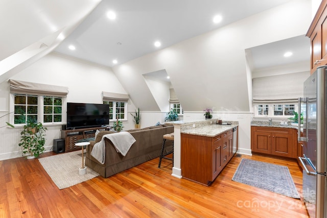 living room featuring lofted ceiling, light wood-type flooring, and sink