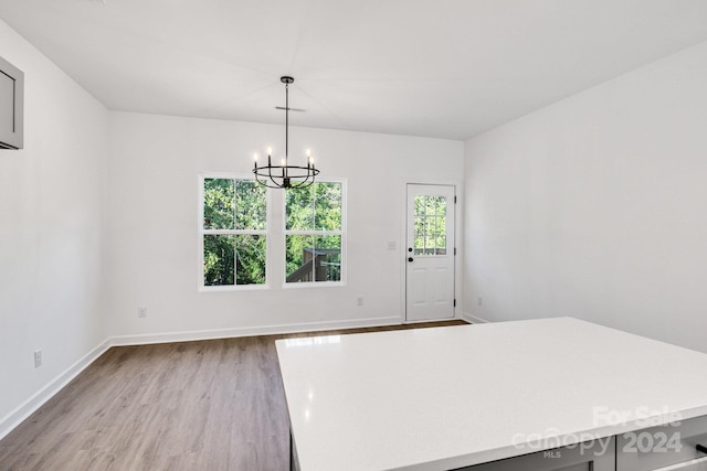 unfurnished dining area featuring a chandelier and light hardwood / wood-style flooring