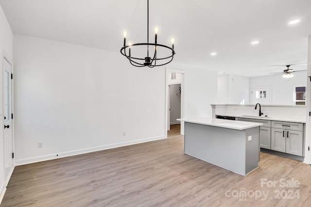 kitchen featuring decorative light fixtures, light hardwood / wood-style floors, a kitchen island, sink, and gray cabinetry