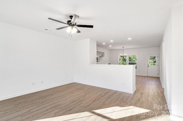 empty room featuring light hardwood / wood-style floors and ceiling fan with notable chandelier