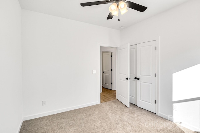 unfurnished bedroom featuring ceiling fan, light colored carpet, and a closet