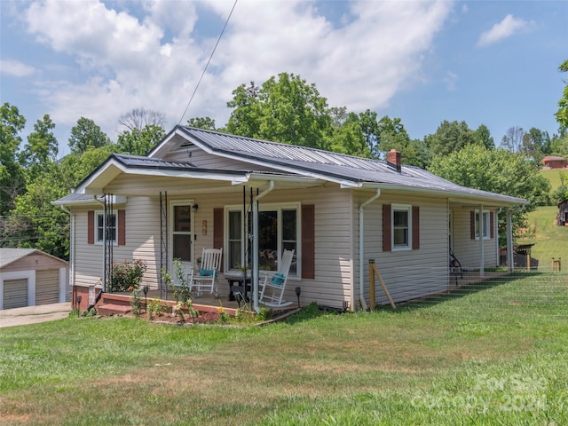 view of front of home with a porch, an outbuilding, and a front yard