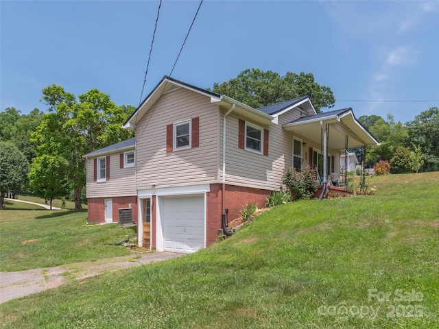 view of home's exterior featuring a garage, a yard, central AC unit, and covered porch