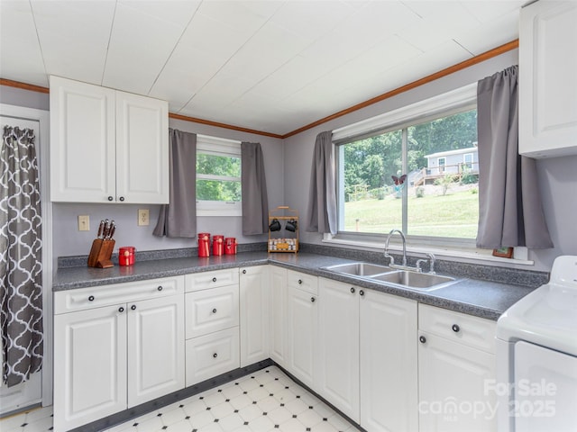 kitchen with crown molding, washer / dryer, sink, and white cabinets