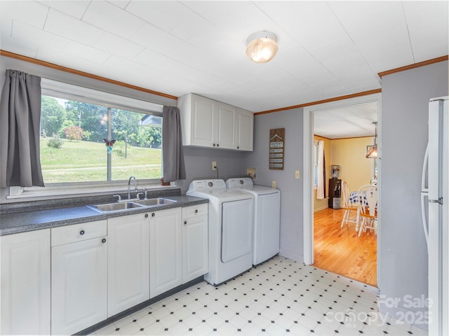 clothes washing area with crown molding, cabinets, separate washer and dryer, and sink