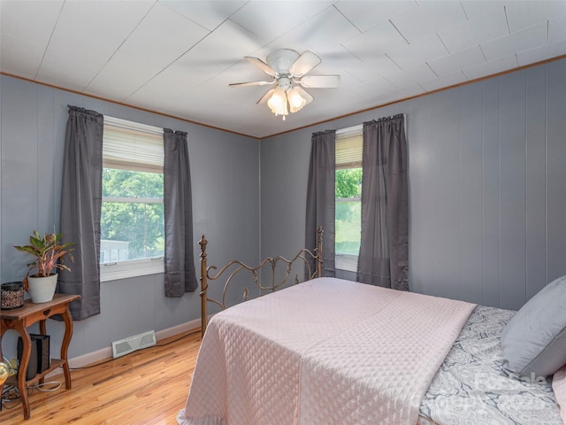 bedroom with multiple windows, ceiling fan, ornamental molding, and light wood-type flooring