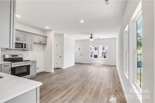 kitchen featuring light hardwood / wood-style floors, appliances with stainless steel finishes, ceiling fan, and backsplash