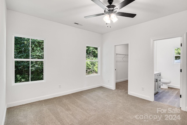 unfurnished bedroom featuring multiple windows, light colored carpet, and a spacious closet