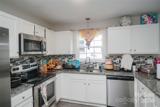 kitchen with pendant lighting, white cabinets, appliances with stainless steel finishes, decorative backsplash, and sink