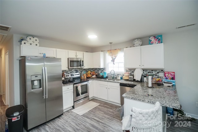 kitchen featuring white cabinetry, kitchen peninsula, stainless steel appliances, hanging light fixtures, and sink